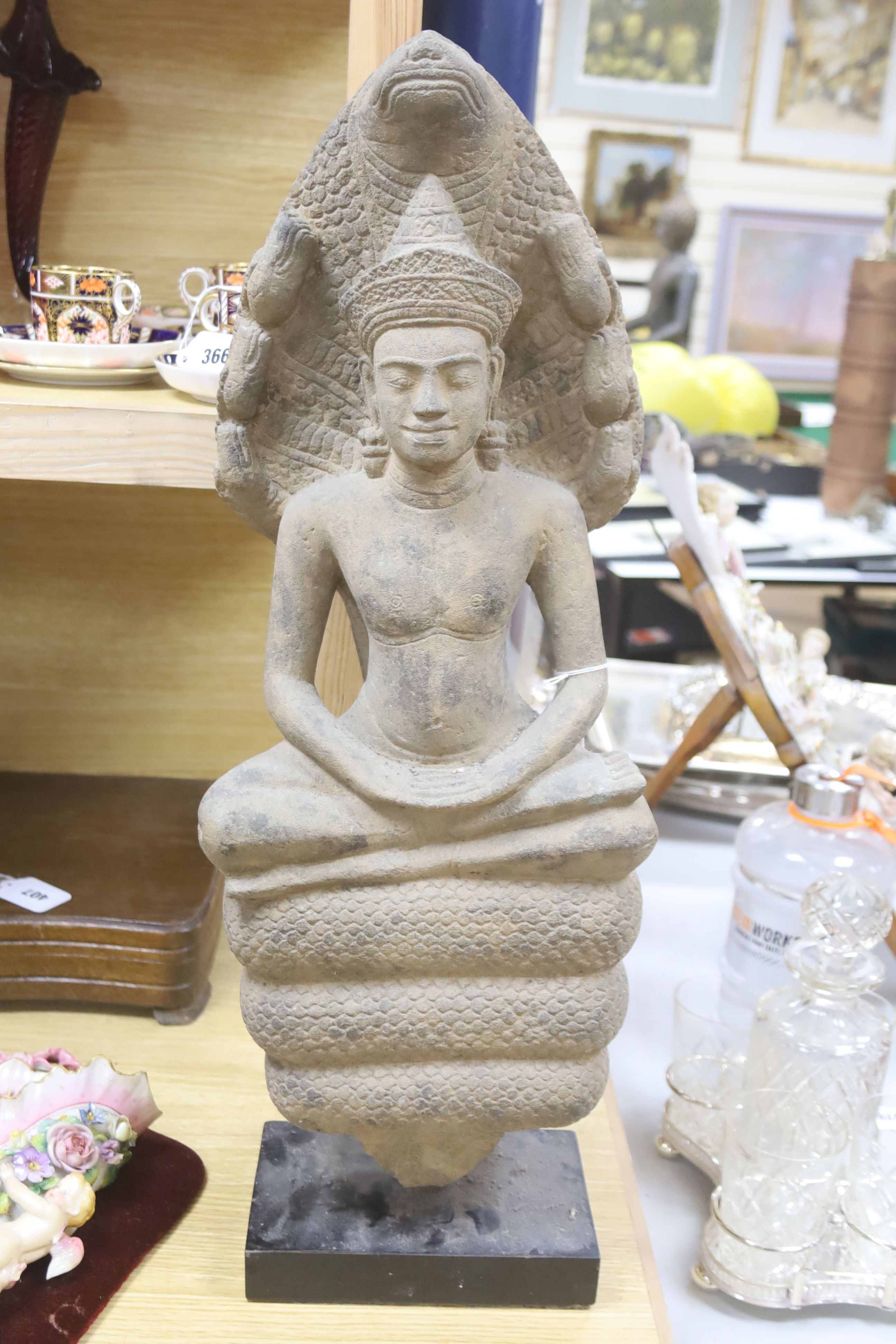 A large stone figure in the style of a Cambodian Buddha, on stand, height 68cm